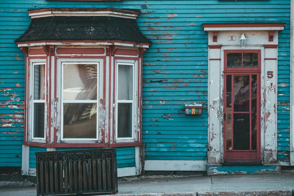 Aged blue painted wall with a window and door