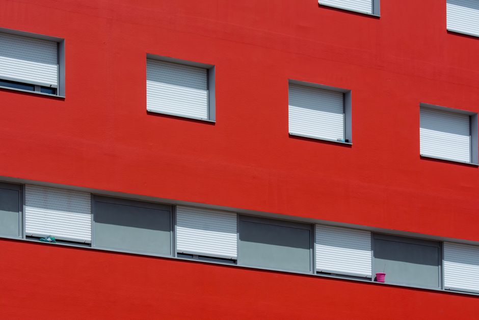 Red painted building wall with closed shutters