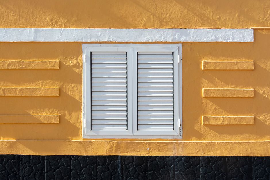 Yellow painted wall with white shutters