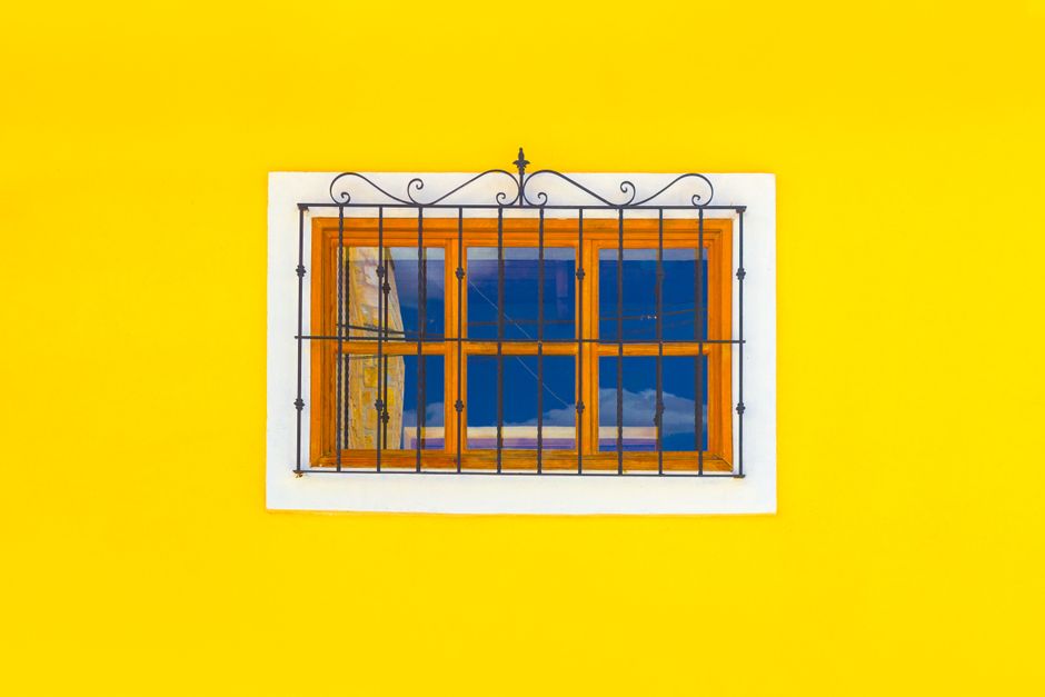 Small wood framed window on a painted yellow wall
